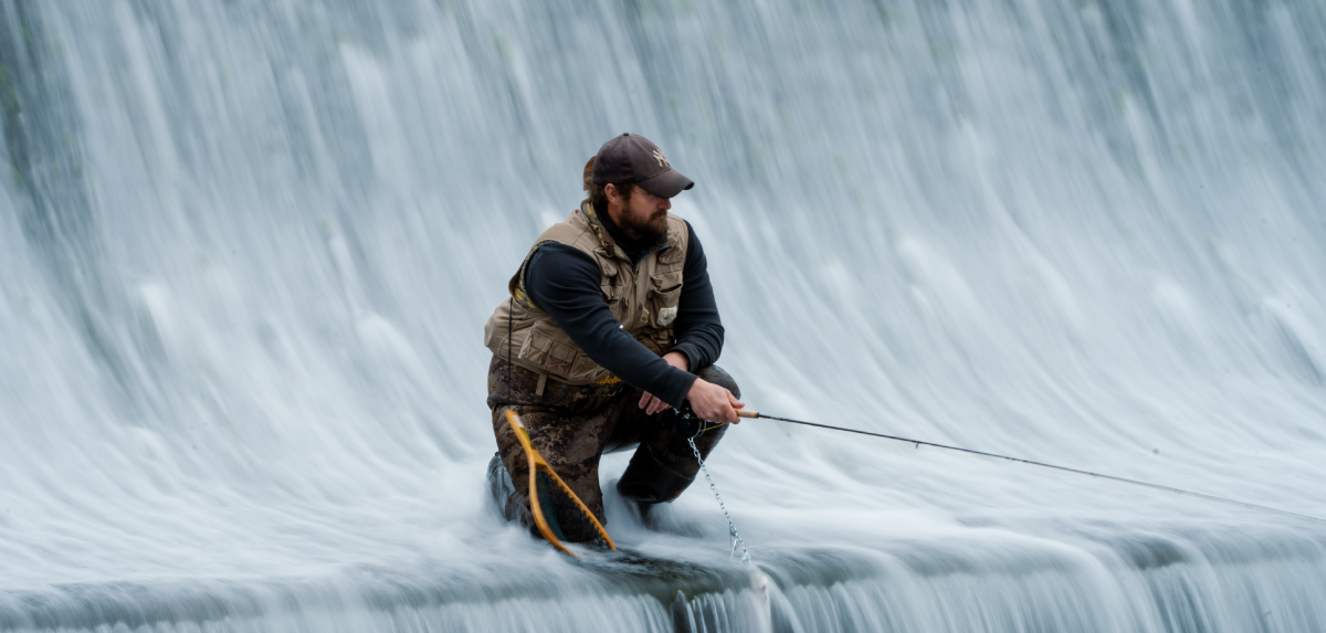 A man trout fishing in the middle of a dam.