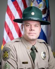 Ranger Brandon Bart standing in-front of a flag