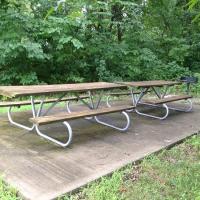 two picnic tables end-to-end on a concrete pad