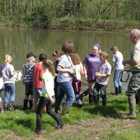 a group of kids listening to a nature program by the lake